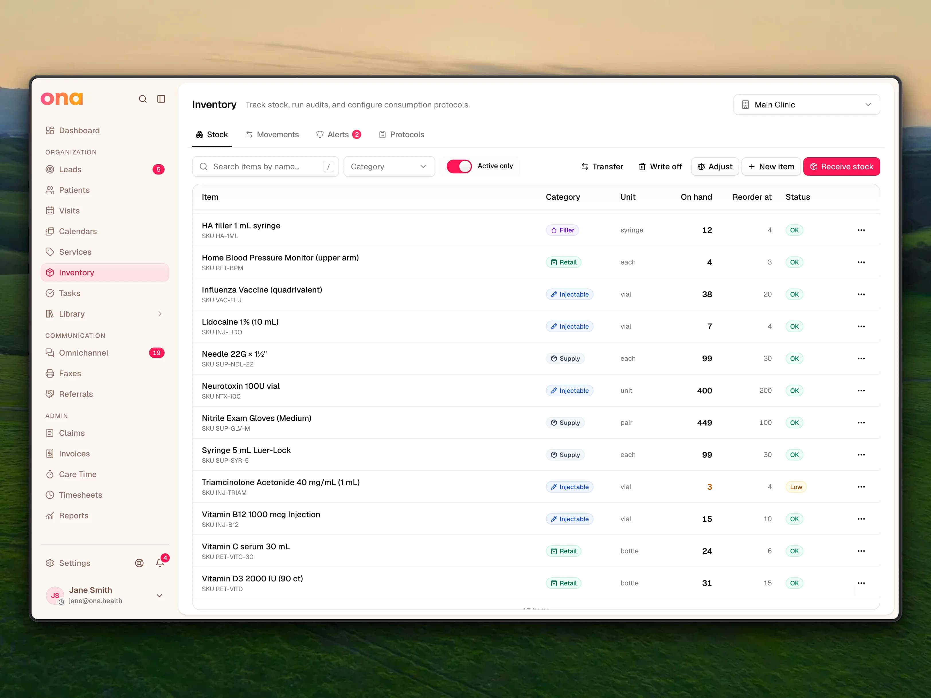 The Inventory page on the Stock tab with the Main Clinic location selected and a table of items such as the Neurotoxin 100U vial, HA filler 1 mL syringe and Vitamin C serum 30 mL, showing each item's category, unit, quantity on hand, reorder level and status
